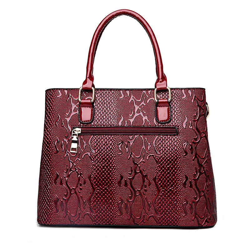 Deep red snake-print structured tote with a secure zip closure, ideal for everyday organization.