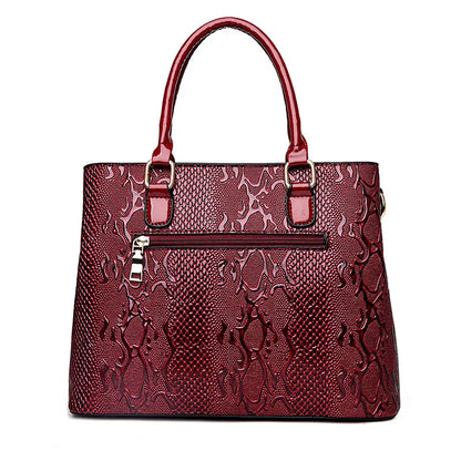 Deep red snake-print structured tote with a secure zip closure, ideal for everyday organization.