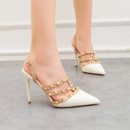 Beige and white pointed-toe ankle strap heels with gold rivets for office wear.