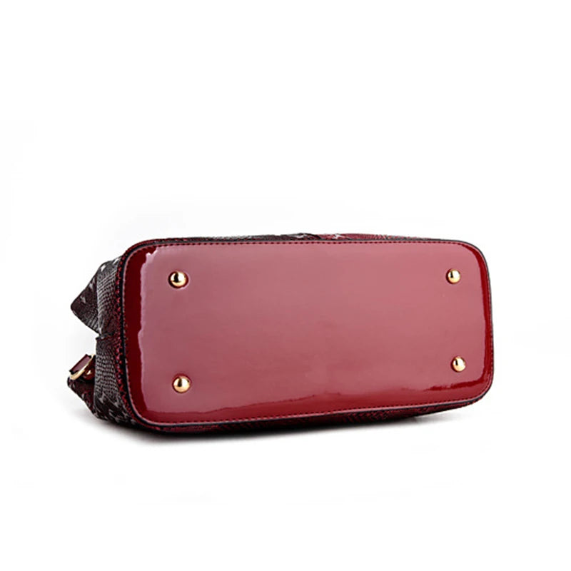 Red faux leather structured shoulder tote with metal feet for travel.