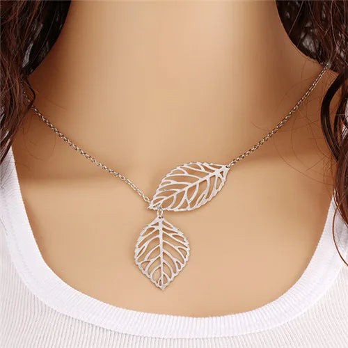 Silver-tone metal leaf-pendant necklace on a delicate chain, worn around the neck.