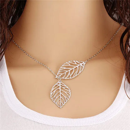 Silver-tone metal leaf-pendant necklace on a delicate chain, worn around the neck.