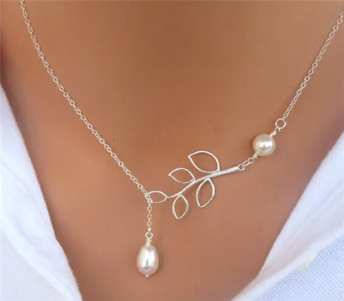 Silver chain necklace featuring an asymmetrical branch pendant with wire leaves and white pearls.
