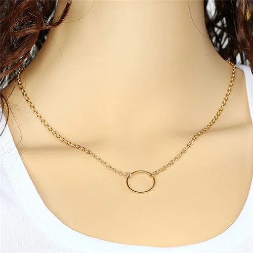 Gold-colored metal chain necklace featuring a small circular ring pendant centered on the collarbone.