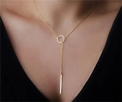 Gold-colored lariat necklace featuring a delicate chain, small metal ring, and vertical bar pendant.