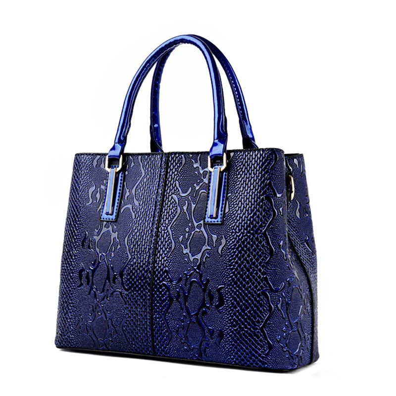 Blue structured tote bag with glossy snakeskin texture, dual handles, and zip closure for daily essentials.