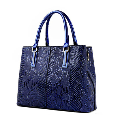 Blue structured tote bag with glossy snakeskin texture, dual handles, and zip closure for daily essentials.