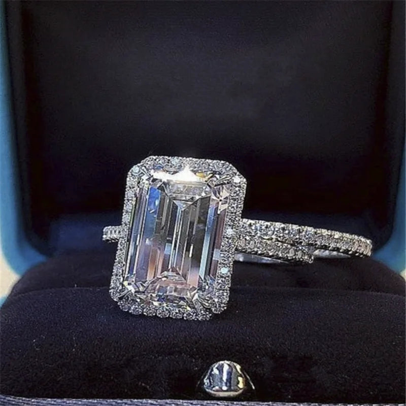 Two-piece silver ring set featuring a large emerald-cut center stone with pavé halo and bands.