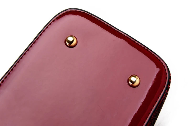Shiny deep red faux leather structured bag base with gold protective feet for daily carry.