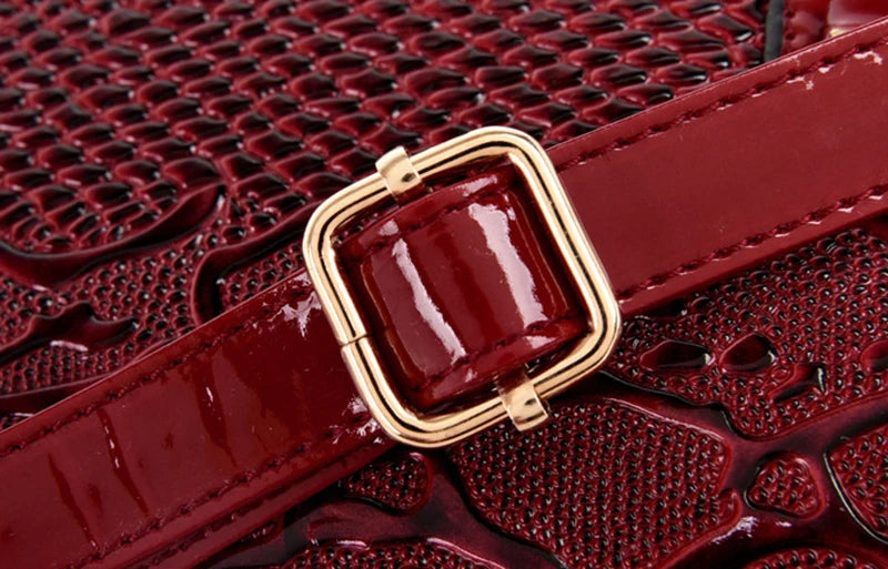 Dark red faux leather shoulder tote with gold buckle and adjustable strap for daily carry.