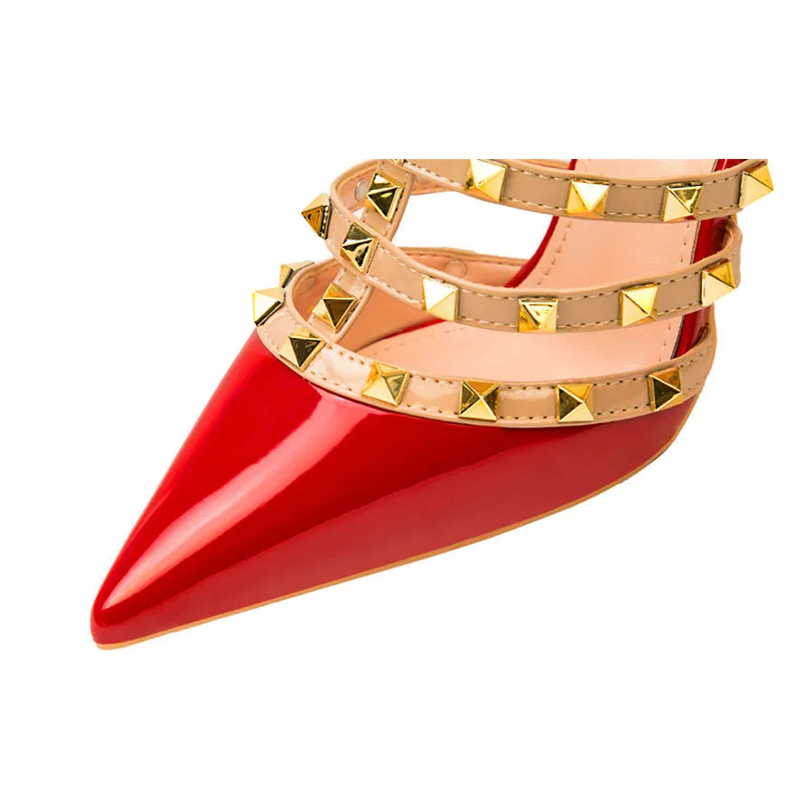 Red patent leather pointed-toe ankle strap pumps with gold pyramid studs for office wear.