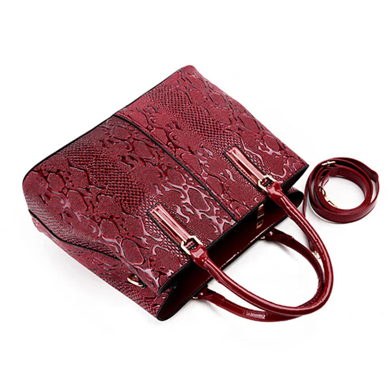 Red snake-embossed faux leather structured crossbody bag with top handles and an adjustable strap for daily carry.