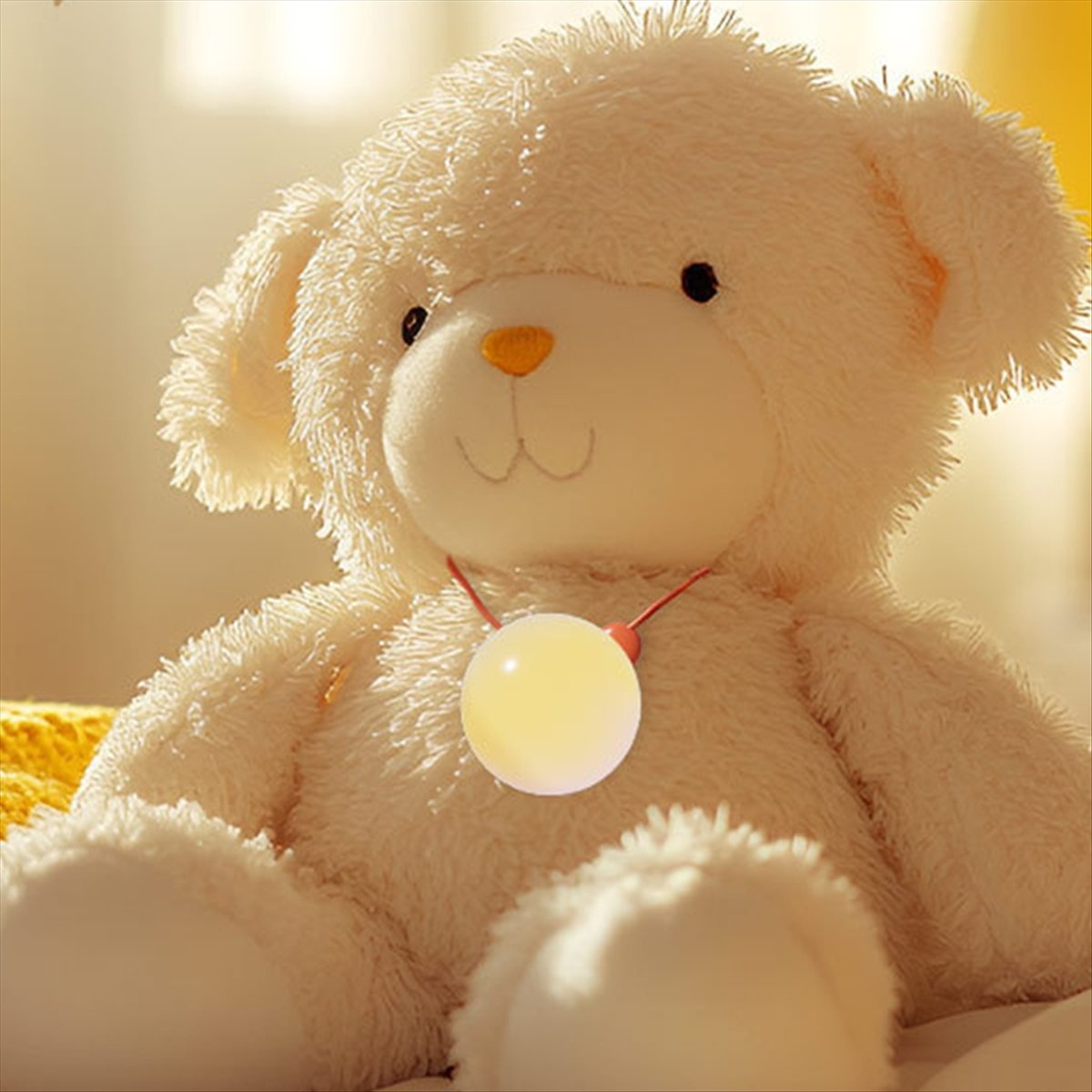 Plush teddy bear toy with glowing Knowledge Bubble pendant; cream fur, red cord