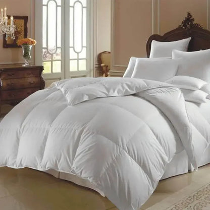 Fluffy white goose down comforter on a made bed with matching pillows and white linens.