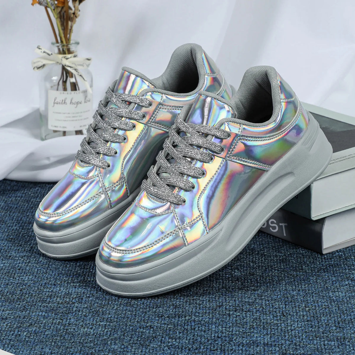 Silver holographic lace-up sneakers with thick grey soles and glittery laces.