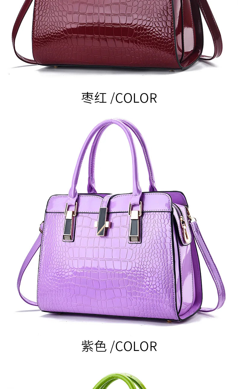 Glossy purple and maroon crocodile-pattern leather handbags with dual top handles and gold-tone hardware.