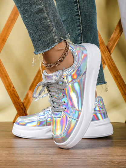 Holographic silver lace-up casual sneakers with thick white soles worn with blue jeans.