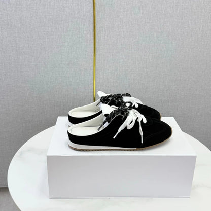 Black suede slip-on shoes with white laces and trim, round toes, and flat soles.
