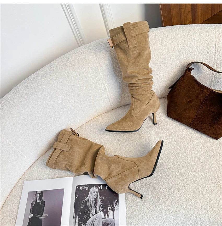 Camel suede high-heel slouchy boots with pointed toe, thin heel, and a decorative top belt buckle.