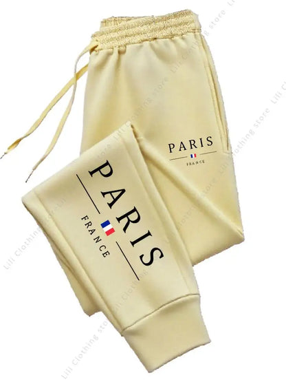 Pale yellow fleece-lined joggers with Paris graphic print and stretchy drawstring waist for comfortable lounging.