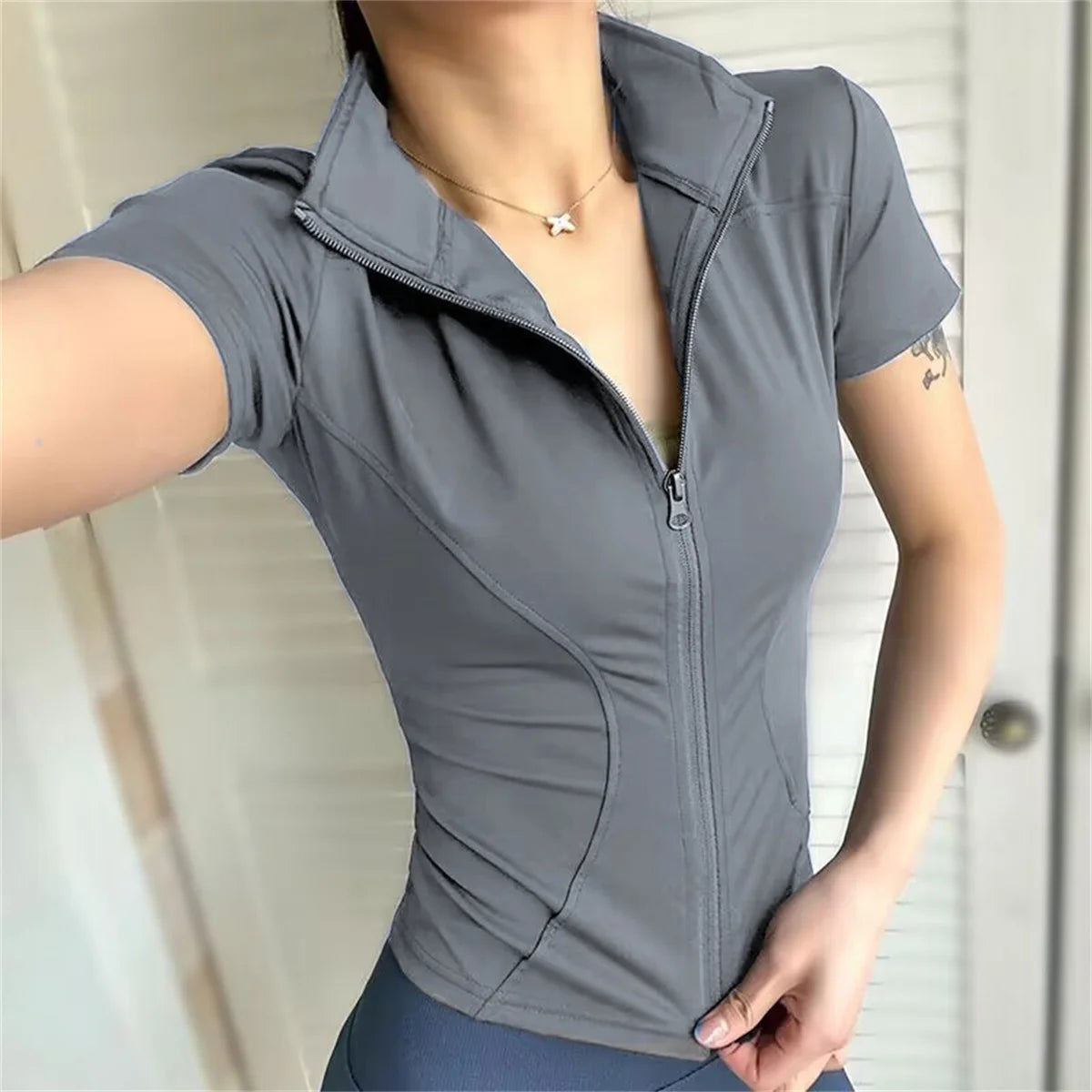 Grey polyester sports jacket with a zip front and fitted design for running, cycling, and yoga.