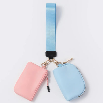 Pink and blue nylon dual pouch wallet with a zip closure and blue adjustable strap for carrying cards on the go.
