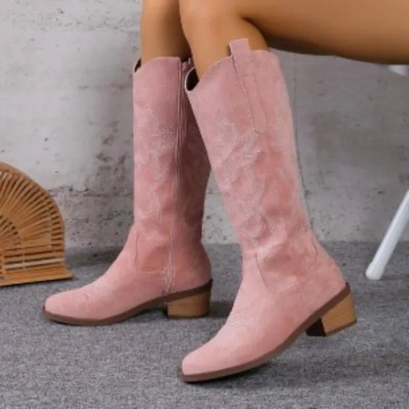Pink suede knee-high western cowboy boots with chunky block heels and tonal shaft embroidery.