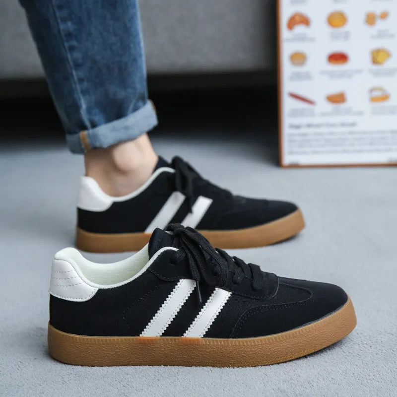 Black canvas sneakers with white stripes and gum soles. Breathable casual training shoe for daily wear.