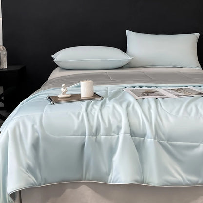 Light blue cooling comforter with smooth moisture-wicking fabric for hot sleepers on a made bed.