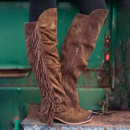 Brown suede over-the-knee boots with long side fringe, ankle buckle straps, side zippers, and thick heels.