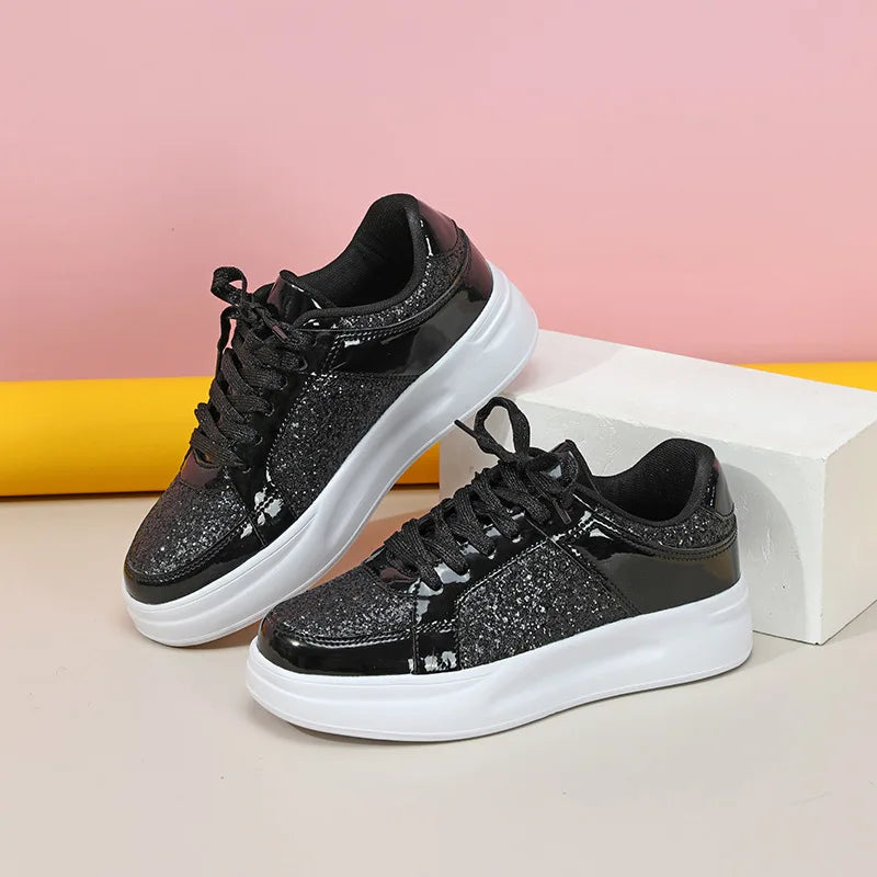 Black lace-up casual sneakers with sparkly glitter panels, patent leather trim, and thick white soles.