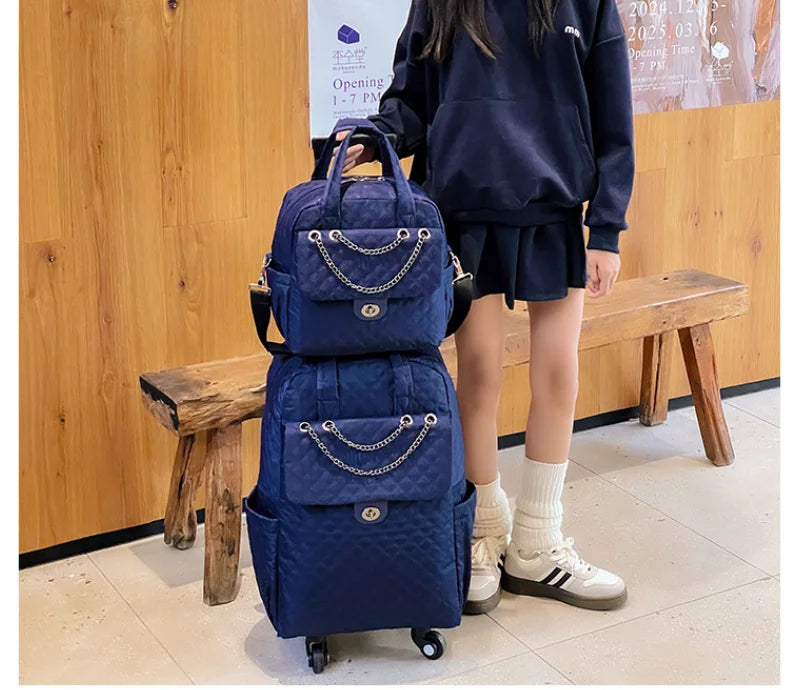 Dark blue quilted rolling travel backpack with chain details, top handle, and front pocket flap.