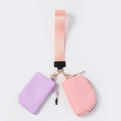 Pink and purple nylon dual pouch with a zip closure and peach wrist strap for carrying cards and keys.