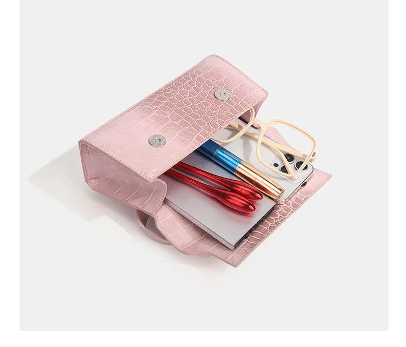 Pink faux leather crossbody with croc texture, snap closure, and organized essentials for daily errands.