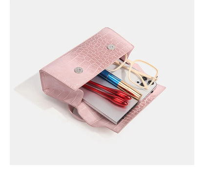 Pink faux leather crossbody with croc texture, snap closure, and organized essentials for daily errands.