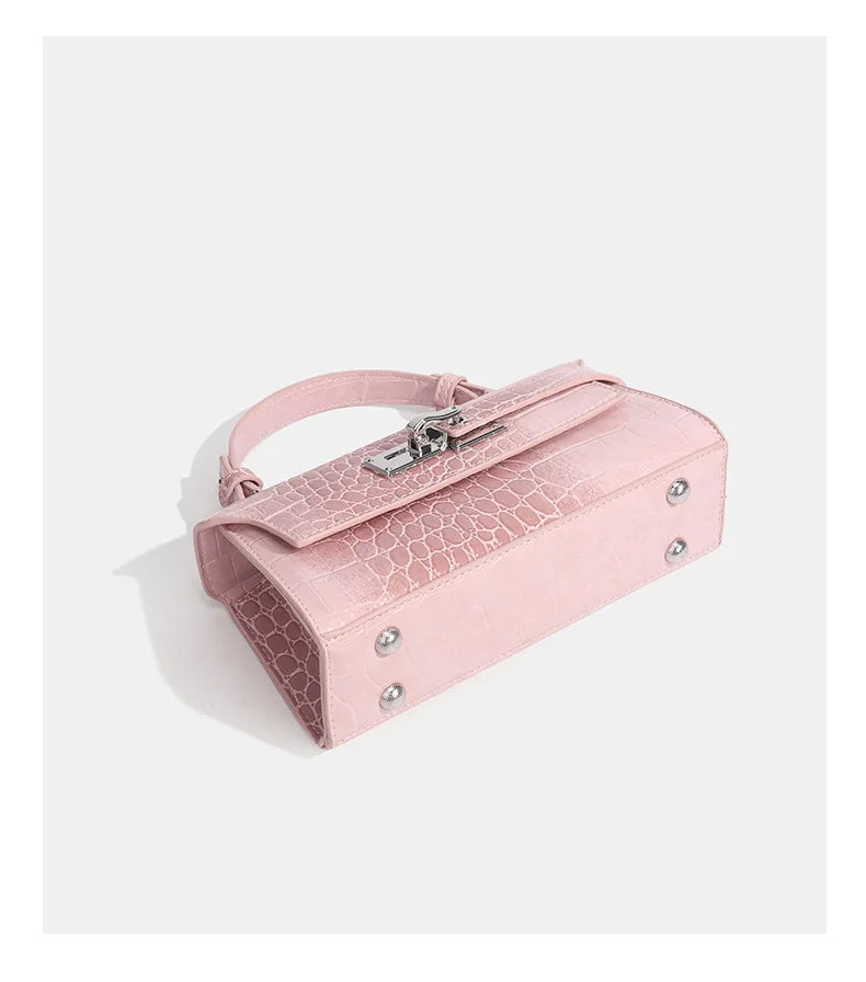 Pink crocodile-embossed faux leather structured crossbody bag with a metal latch and handle for daily outings.