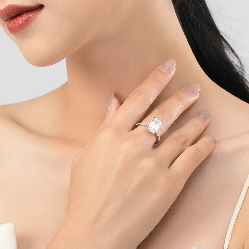 Silver sterling ring with a large rectangular cut cubic zirconia stone and pavé band worn on a finger.
