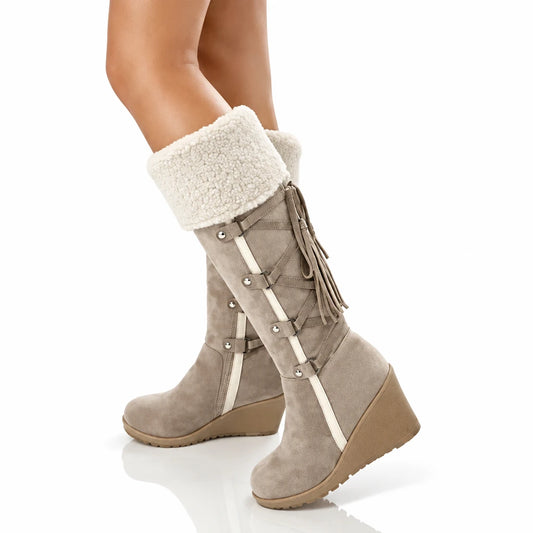 Tan wedge mid-calf boots with white shearling cuffs, side tassels, and decorative straps.