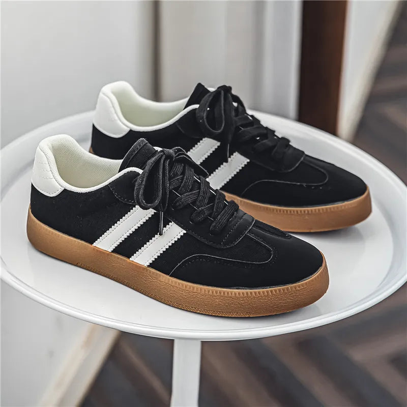Black canvas sneakers with white stripes, laces, and gum soles. Breathable casual training shoe for daily exercise.