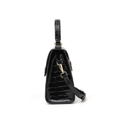Black glossy crocodile-pattern leather handbag with top handle, gold hardware, and detachable shoulder strap.