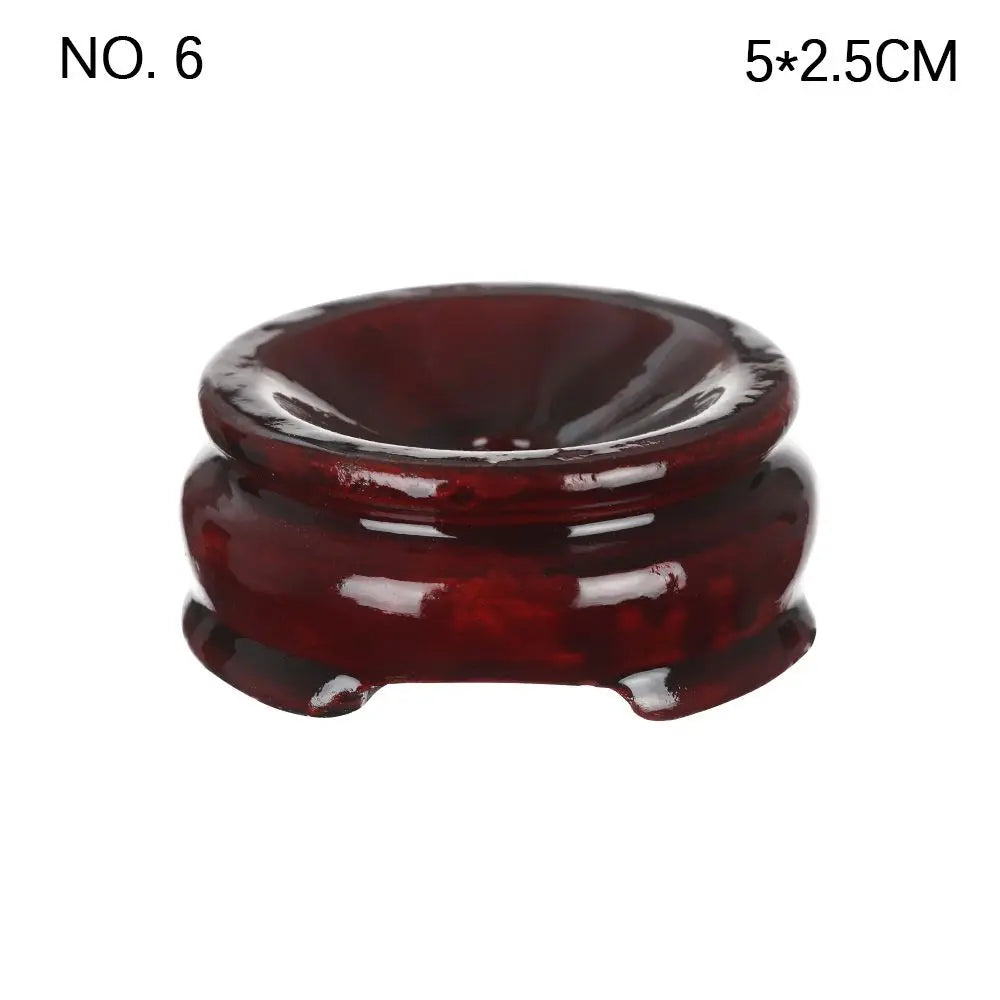 Dark reddish-brown polished wooden crystal ball stand with a rounded, recessed top and flared feet.