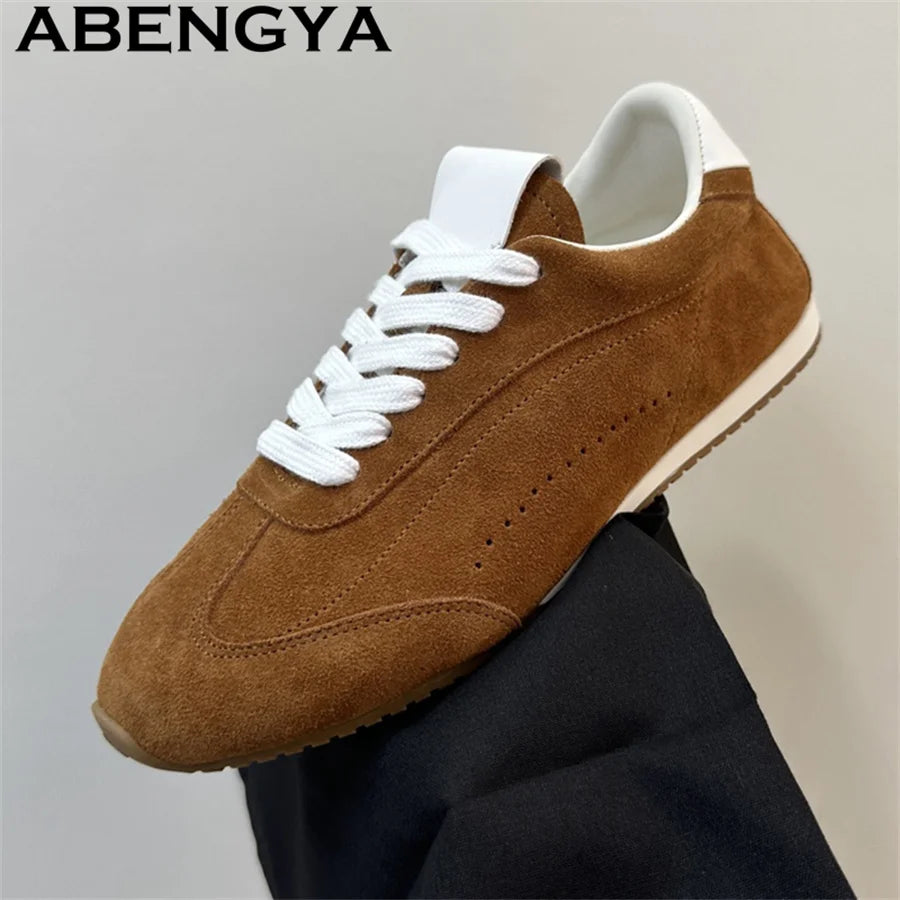 Brown suede lace-up sneaker with white laces, white tongue, and white heel tab on a white and brown sole.