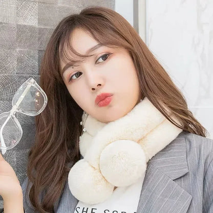 Off-white plush faux fur crossover scarf with two large pom-poms worn around the neck.