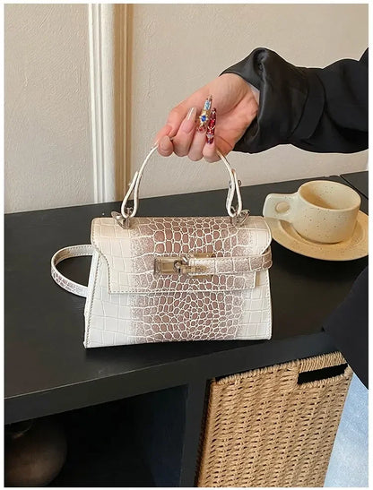 White faux leather crossbody diaper bag with crocodile texture and structured design for carrying baby essentials.