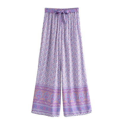 Purple floral flowy wide leg drawstring pants with a detailed bohemian border for beach vacations.