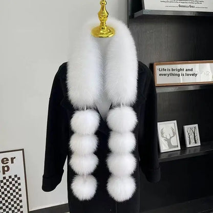 White faux-fur scarf with long ends and four fluffy pom-poms on each side, draped over a black coat.