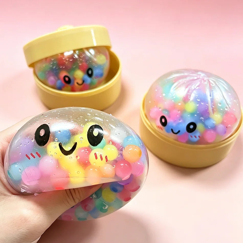 Clear soft foam dumpling squishy fidget toy filled with colorful beads in yellow containers for sensory play.