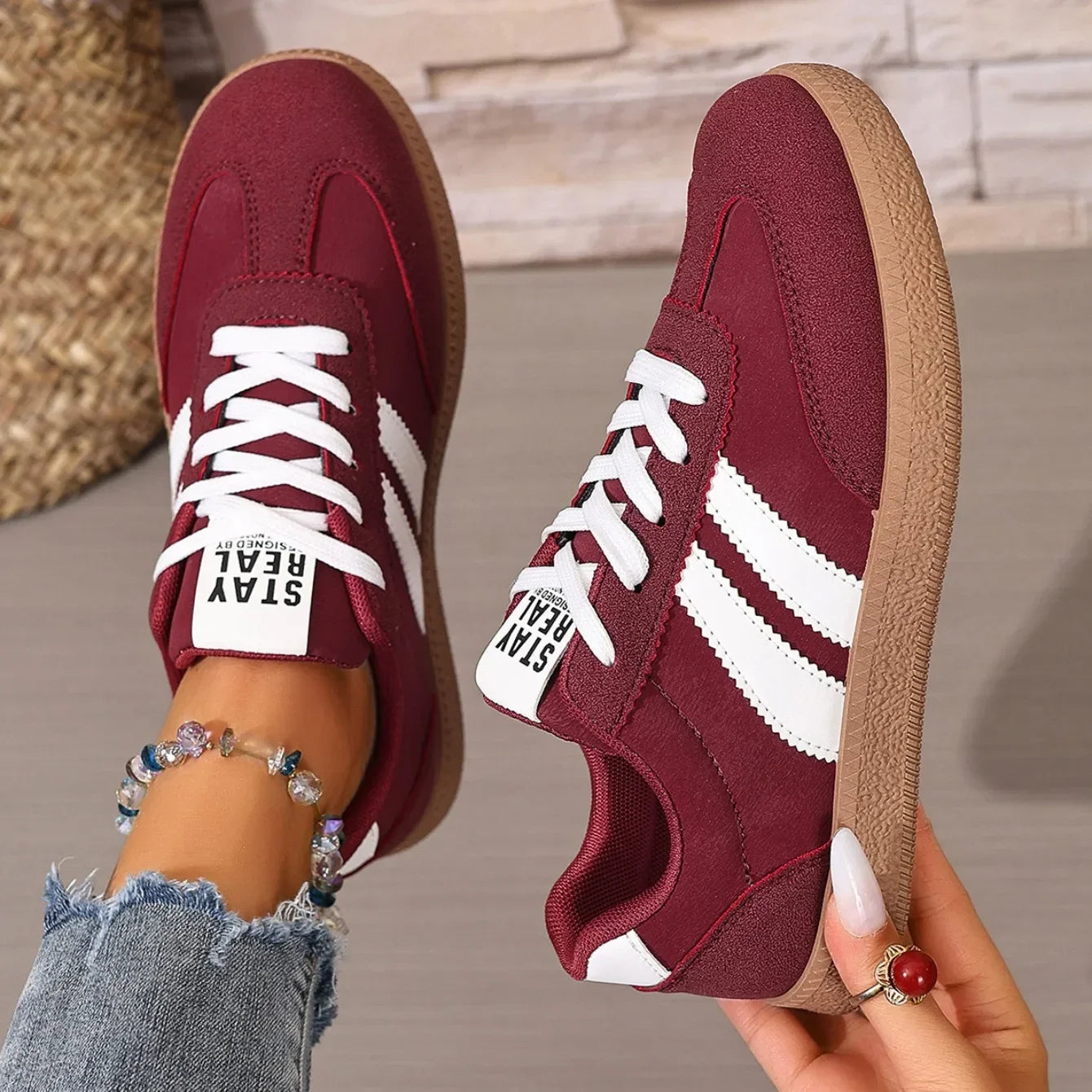 Maroon leather slip-on sneakers with white stripes, white laces, and gum soles for comfortable everyday wear.