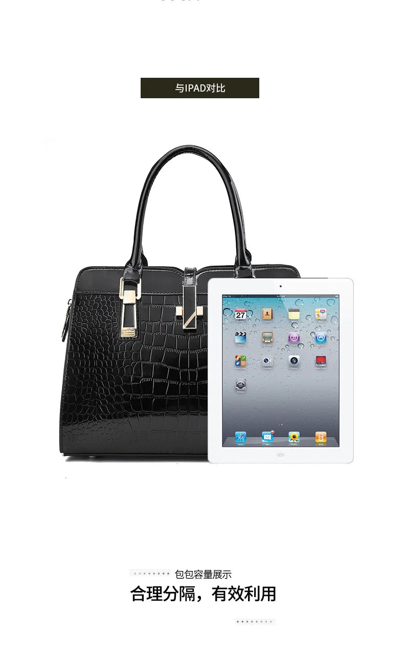 Black crocodile-pattern leather handbag with dual top handles, gold hardware, and a tablet shown for scale.