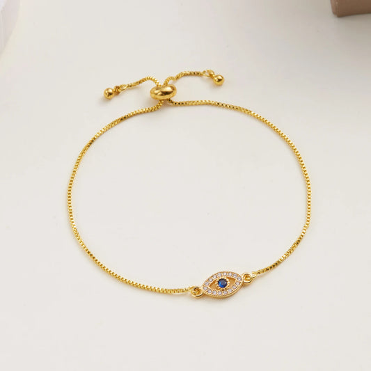 Gold-tone adjustable box chain bracelet featuring a central evil eye pendant with clear and blue stones.